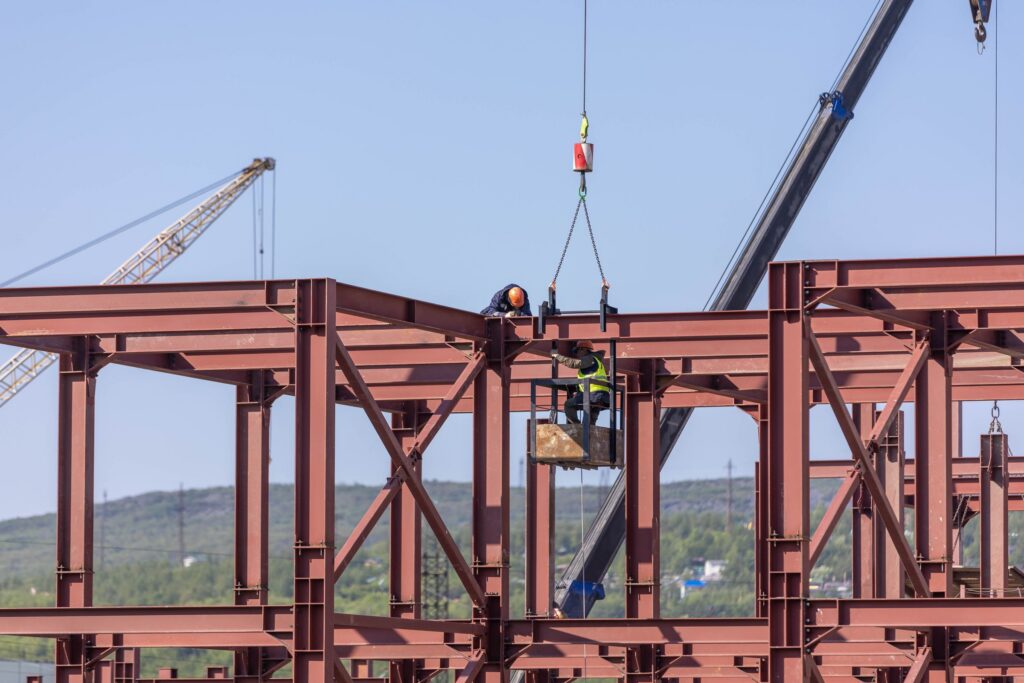 Crane lifting a structural steel beam into place on a construction site